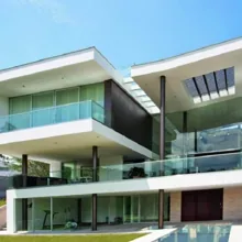 Fachada de residência com fechamentos e guarda-corpos de vidro
